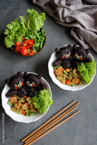 Homemade Japanese cuisine. Sun Bear Onigiri with Thai Green Curry. Delicious and healthy madefrom black rice, cheese, tomatoes, green curry, tempeh, beancurd puff, seaweeds, lolo salad and more photo