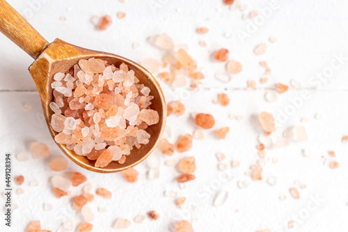 Himalayan Pink Rock Salt. Mineral-rich salt from the Himalayan region. on wooden sponn on wite background