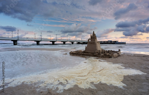 Zamek z piasku na plaży w Kołobrzegu, w pięknych barwach wschodzącego słońca.