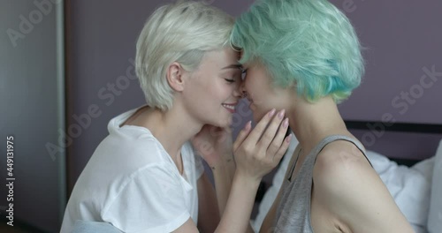 Tender women, lesbian couple kissing each other pssionately sensually, side view. young caucasian girlfriends touching each other, in love. attractive short haired girlfriends in casual domestic wear