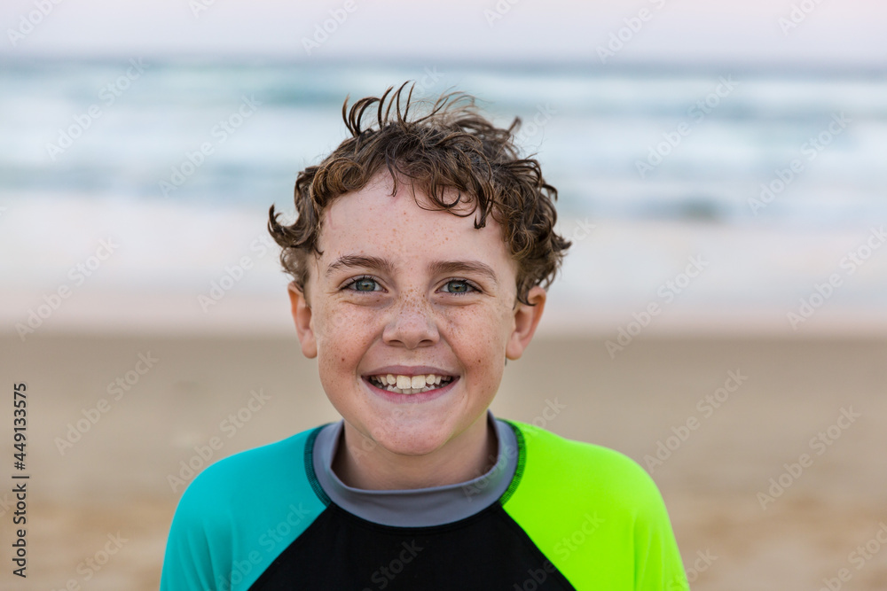 Young boy with freckles and curly hair smiling happy at beach Young boy with freckles and curly hair smiling happy at beach