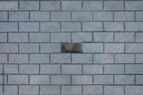 Concrete or paved gray paving slabs or stone flooring top view. One tile is missing in the middle. Reinforced concrete products for road construction.
