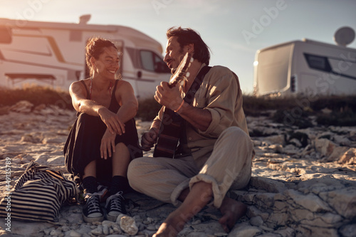 Man singing to his girlfriend on a beach.
