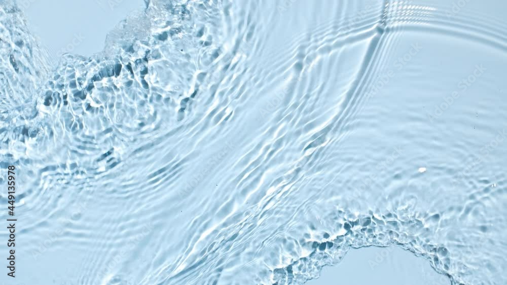Water flows from opposite sides creating waves and ripples on light blue background | Background shot for skincare products commercial