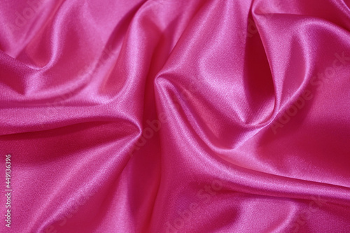 Beautiful bright pink silk satin background. Wavy soft folds. Elegant fabric background with copy space for design. Web banner.