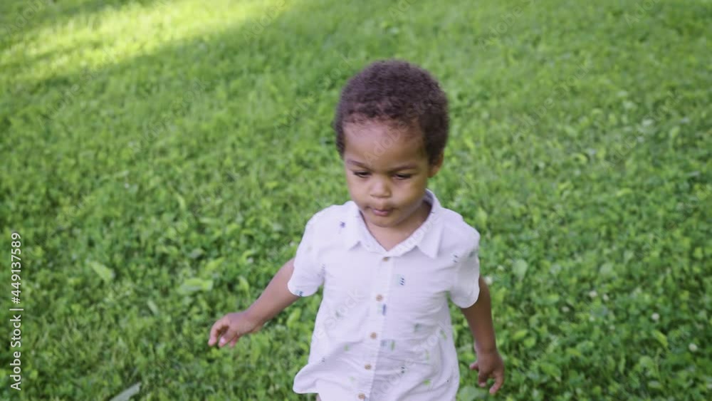 A little African boy happily runs along the green lawn. Happy childhood in nature. A little African boy happily runs along the green lawn. Happy childhood in nature.