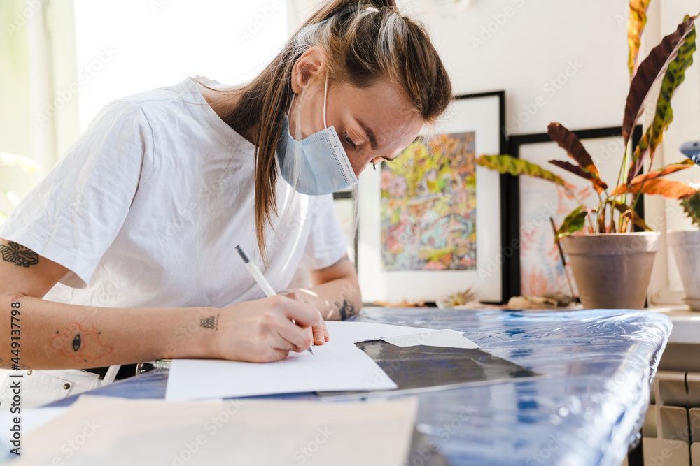 Young white woman doing sketches while working indoors