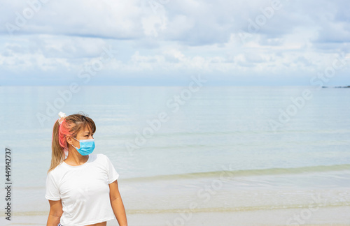 Asian woman standing on sand beach with face mask