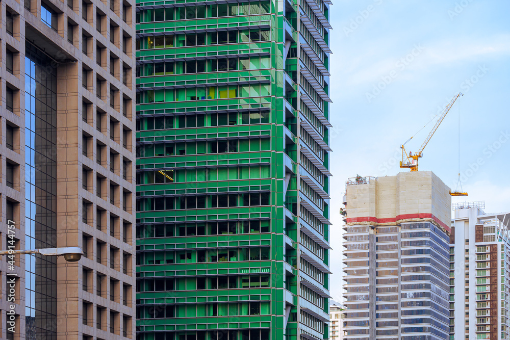Fototapeta premium Focus on foreground at row of high residential buildings with blue sky in perspective side view that one building is under construction 