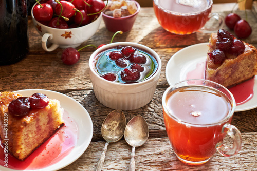 Cherry pie with jam in a bowl. Tea, flowers. Wooden background, side view