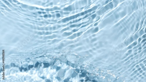 Multiple waves of water cross each other creating ripples spontaneously on pale blue background | Beauty background shot for skin care cosmetics advertisement photo