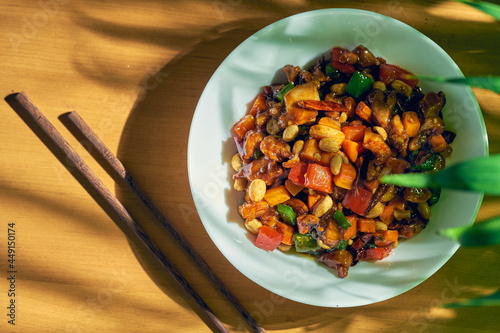 Sweet and sour chicken with wok vegetables, sesame peanuts and Sichuan pepper in a white bowl. Chinese cuisine