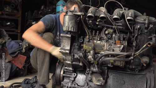 An auto mechanic checks the internal combustion engine. The engine is covered in oil and dirty. Its complete replacement also failed. Auto disassembly or car service .