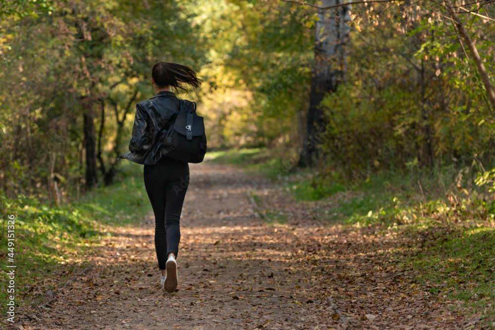 Girl runs along the park alley. Woman runs away from someone in the park. Girl runs along the park alley. Woman runs away from someone in the park.