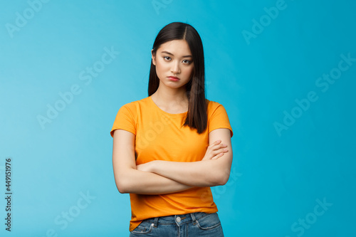 Serious-looking indifferent and upset intense asian woman brunette, cross arms chest look strict ignorant, pissed listening nonsense, annoyed stupid conversation, stand blue background photo