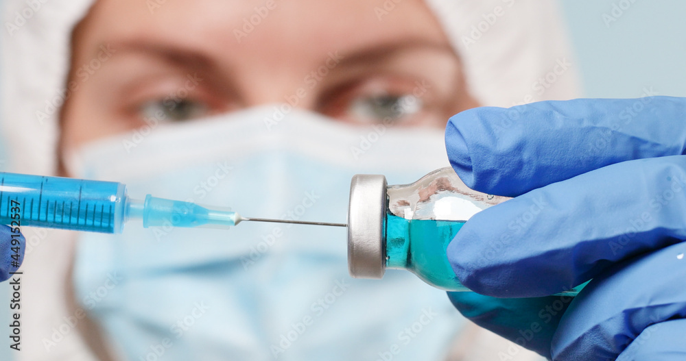 Caucasian female doctor in protective gloves and mask fill syringe with covid-19 vaccine medicine for injection Caucasian female doctor in protective gloves and mask fill syringe with covid-19 vaccine medicine for injection