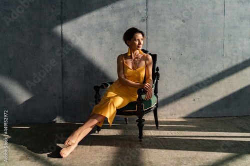 Tableau sur toile attractive woman in yellow summer dress in interior room concrete wall backgroun