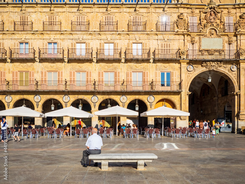 Un hombre mayor sentado en un banco de piedra de la Plaza mayor de salamanca photo