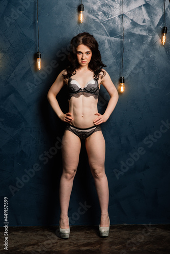 Young beautiful woman body on gray background in black sexy underwear