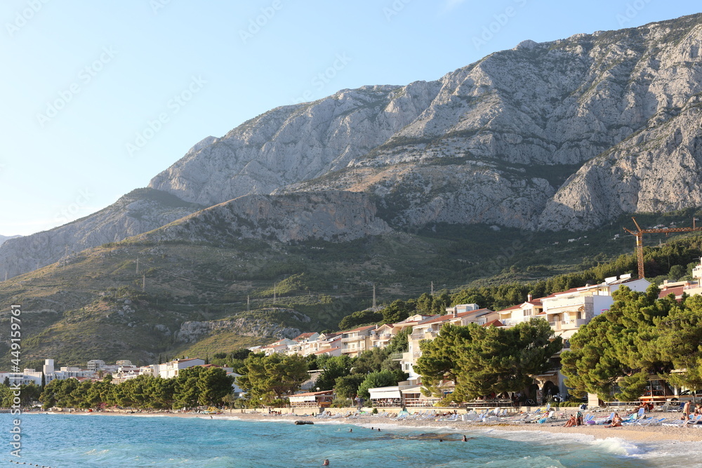 Croatian beach of Tucepi in the evening. Beautiful landscape with shoreline of Makarska Riviera and Adriatic Sea in Croatia on a cloudy day. Seaside view with fresh air from pine trees.