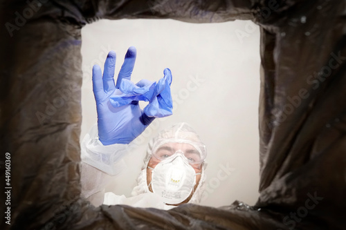man in a protective suit throws used medical glove into a trash can. Bottom view from the trash can. The problem of recycling and pollution of the planet with garbage.