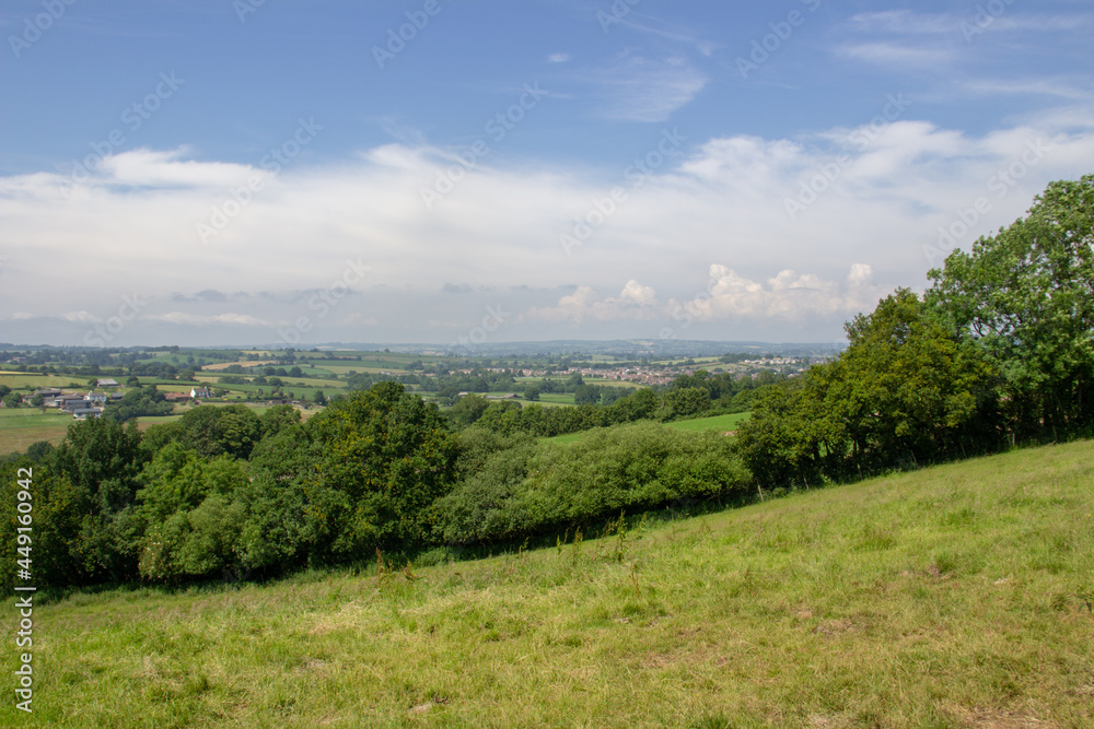 typical Devon rolling countryside with fields, hedges and a cloudy blue sky