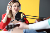 Woman singer in headphones singing song into microphone in recording studio