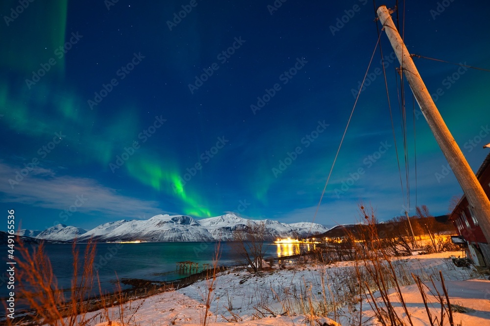 Northern lights over the snow capped mountains in the night in the arctic area of Norway