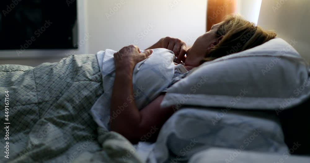 Older woman turning bedside lamp on unable to sleep, waking up in the middle of the night Older woman turning bedside lamp on unable to sleep, waking up in the middle of the night