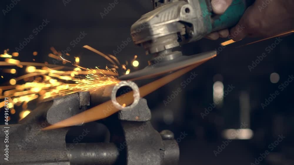 man works with a circular saw. Sparks fly from the hot metal. man was working hard on steel. Close-up, slow motion in garage. An angle grinder cuts an iron billet clamped in a locksmith's vise. man works with a circular saw. Sparks fly from the hot metal. man was working hard on steel. Close-up, slow motion in garage. An angle grinder cuts an iron billet clamped in a locksmith's vise.