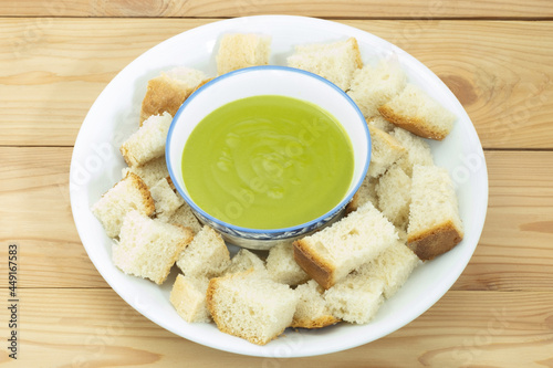 Steamed homemade bread and pandan custard in white ceramic plate on wooden backgroud. Thai dessert.