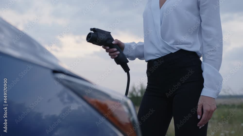 View of a girl'd body, charge of electric car View of a girl'd body, charge of electric car