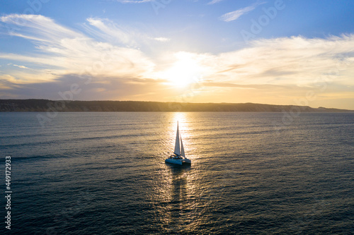 Leinwand Poster Catamaran sailing at sunset