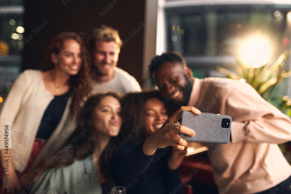 Friends in bar taking selfie on phone