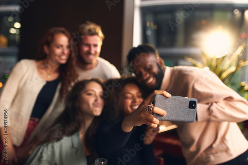 Friends in bar taking selfie on phone