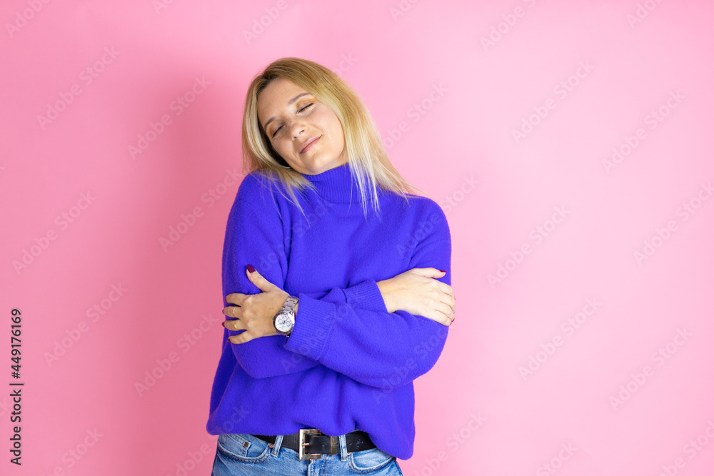 Young beautiful woman wearing casual sweater over isolated pink background hugging oneself happy and positive, smiling confident Young beautiful woman wearing casual sweater over isolated pink background hugging oneself happy and positive, smiling confident