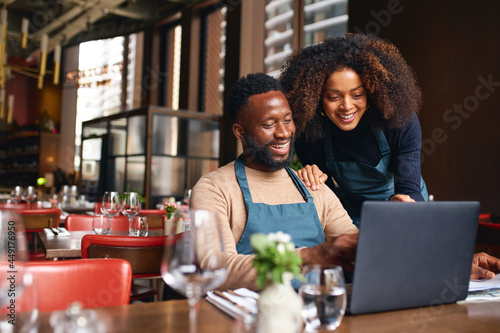 Small business owners using laptop in restaurant photo