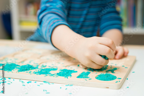 Kid learning numbers through game. Sensory activity with colored rice and wooden numbers. Educations at home  pre-school education  Montessori methodology