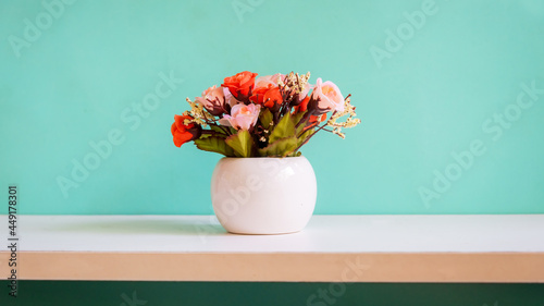 Green wall with flower on shelf white wood for interior at home. copy space for banner text. Still life and Lifestyle Concept