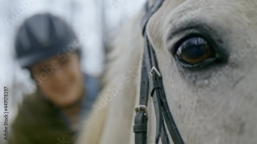 Close up of teen age girl stroking horse in slow motion. Portrait of a girl on horseback, Horse riding camp for children. Child with white horse enjoying ride. Love and friendship concept.