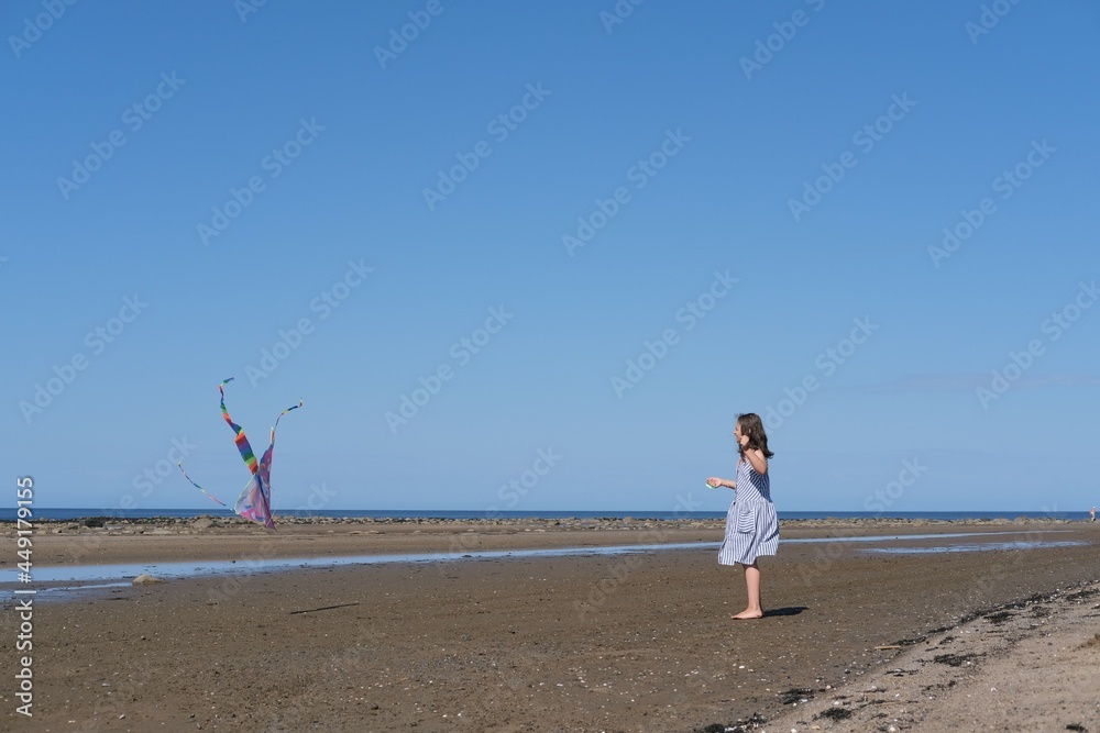 Cute little girl flying rainbow kite on sea beach Cute little girl flying rainbow kite on sea beach