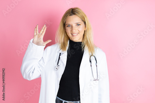 Young blonde doctor woman wearing stethoscope standing over isolated pink background doing star trek freak symbol
