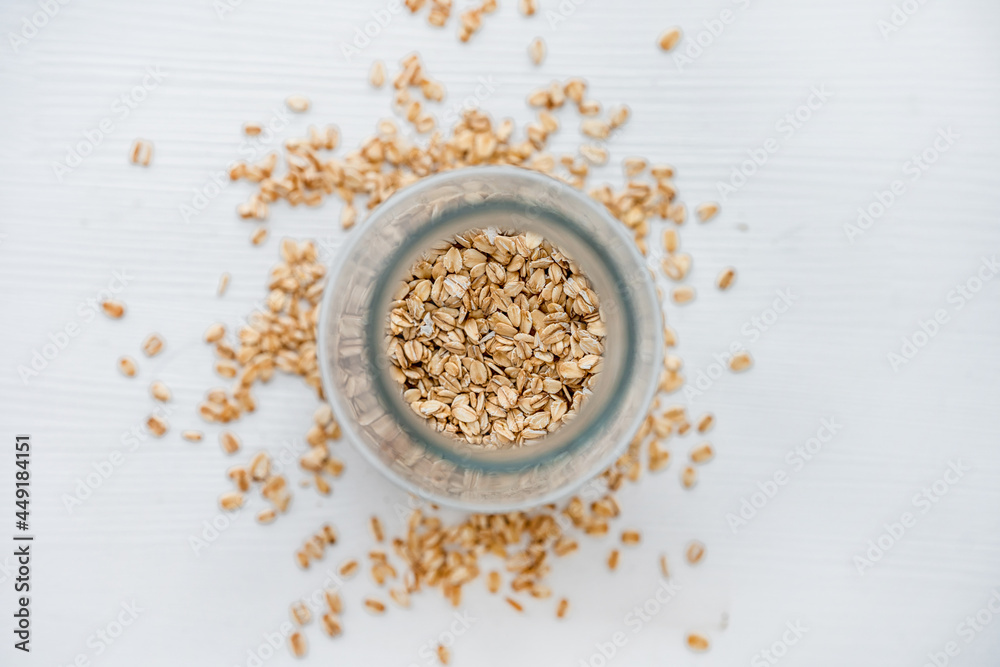 Oatmeal on a white background scattered from a glass jar. Appetizing minimalism Oatmeal on a white background scattered from a glass jar. Appetizing minimalism