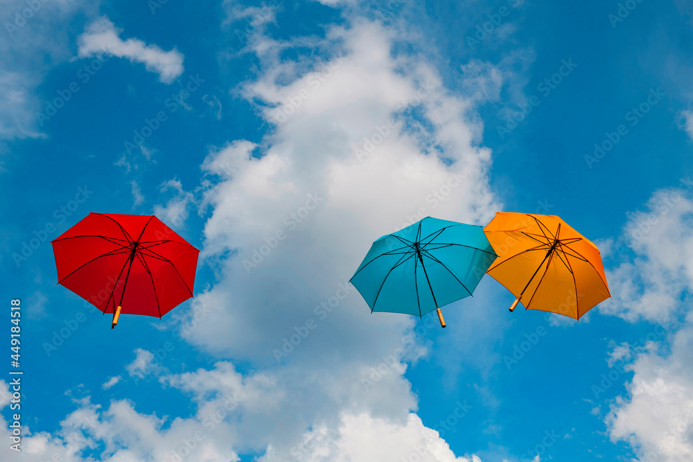 Three stretched out flying colored umbrellas in front of a cloudy sky 5788