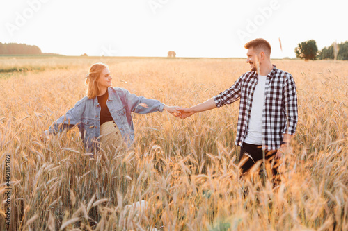 Together into new life is motto of young pregnant couple walking in field on summer evening at sunset. Pregnancy and care. Happiness and tenderness. Love and hope . A healthy lifestyle