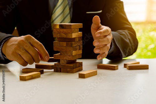 Businessmen build wooden block towers as a symbol of development and planning in business. Strategies for success and planning. Risk gambling placing wooden blocks on towers.
