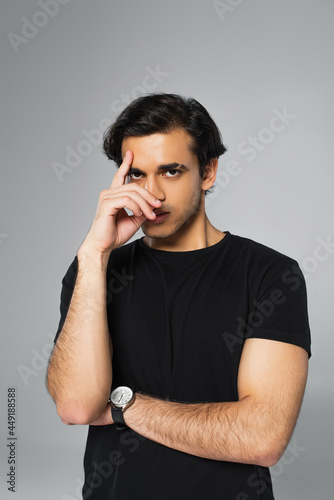 young man in black t-shirt posing and looking at camera isolated on grey