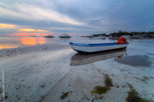 a small boat on the sand at sunset