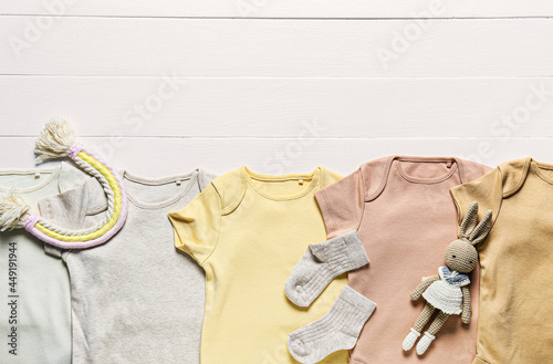 Set of baby clothes and toys on light wooden background, closeup