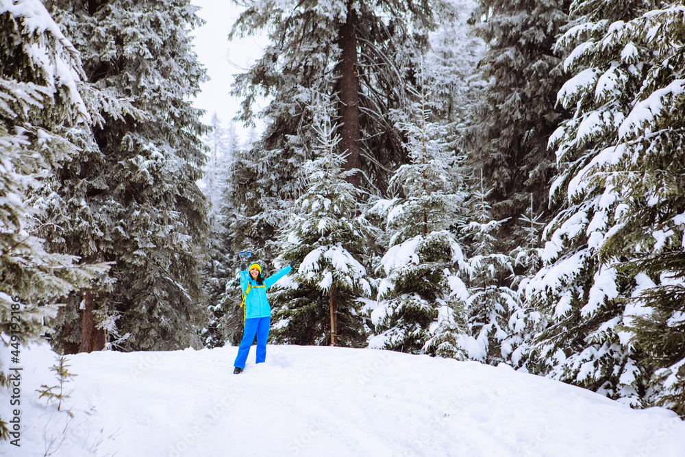 woman walking by snowed forest shooting on the phone